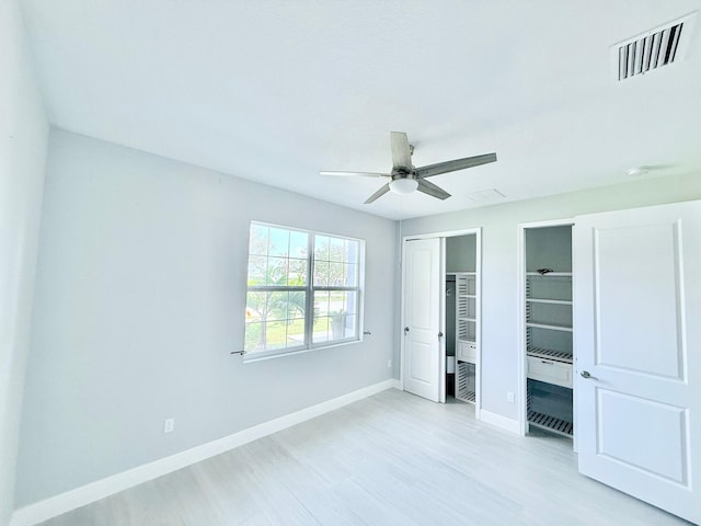 unfurnished bedroom with ceiling fan, visible vents, multiple closets, baseboards, and light wood-type flooring