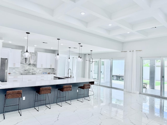 kitchen featuring a kitchen bar, white cabinetry, light countertops, and decorative light fixtures