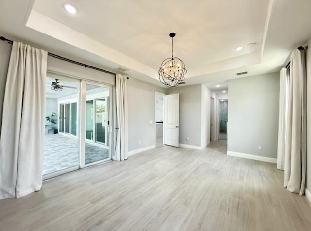 unfurnished dining area featuring baseboards, a raised ceiling, and light wood-style floors