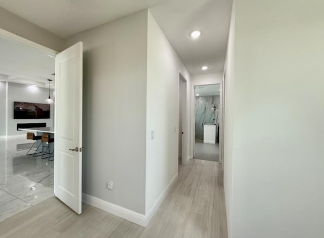 hallway featuring baseboards, recessed lighting, and light wood-style flooring