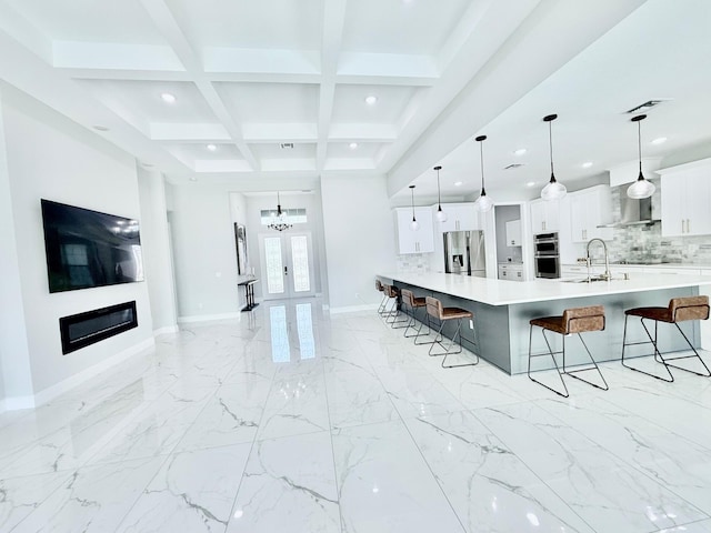 kitchen with appliances with stainless steel finishes, a breakfast bar, hanging light fixtures, light countertops, and white cabinetry