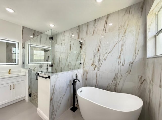 full bathroom featuring vanity, tile walls, recessed lighting, a soaking tub, and a marble finish shower