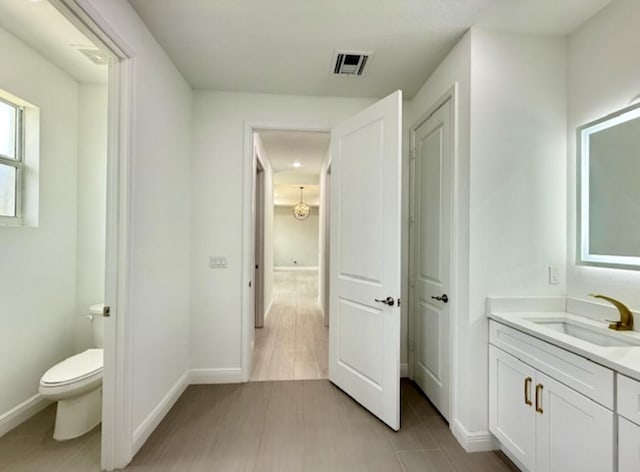 bathroom with tile patterned flooring, vanity, toilet, baseboards, and visible vents