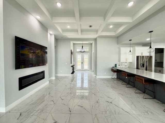 living area featuring baseboards, marble finish floor, a glass covered fireplace, and coffered ceiling