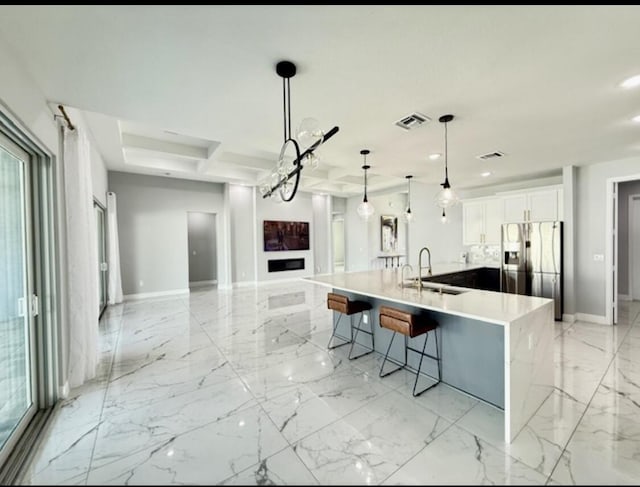 kitchen with a sink, stainless steel fridge with ice dispenser, baseboards, open floor plan, and visible vents