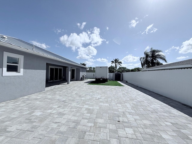 view of patio / terrace featuring a storage unit, a fenced backyard, and an outbuilding
