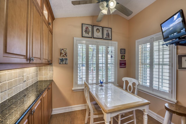 dining room featuring ceiling fan, lofted ceiling, dark hardwood / wood-style floors, and a wealth of natural light