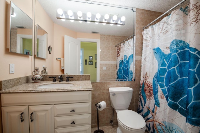 bathroom featuring vanity, toilet, tile walls, and a textured ceiling