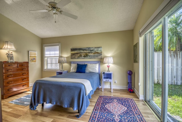 bedroom with lofted ceiling, a textured ceiling, access to outside, ceiling fan, and hardwood / wood-style floors