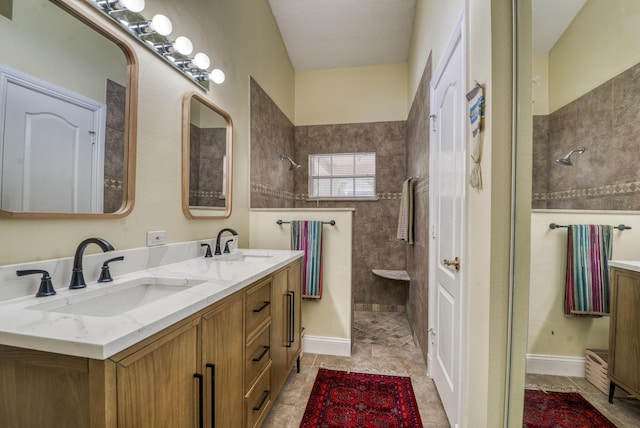 bathroom with tile patterned flooring, vanity, and tiled shower