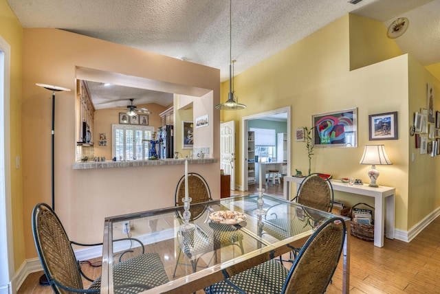 dining space with vaulted ceiling, hardwood / wood-style floors, ceiling fan, and a textured ceiling