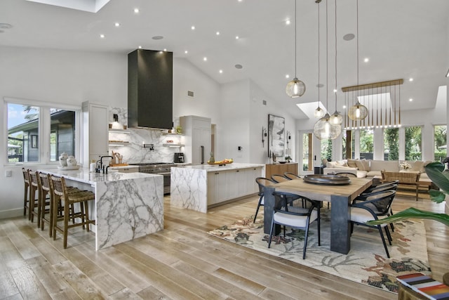 kitchen featuring plenty of natural light, ventilation hood, high end stainless steel range oven, and light wood-style flooring