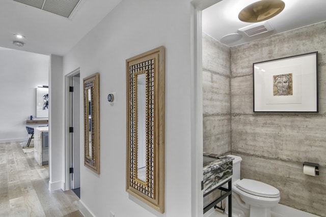 bathroom with baseboards, visible vents, toilet, and wood finished floors