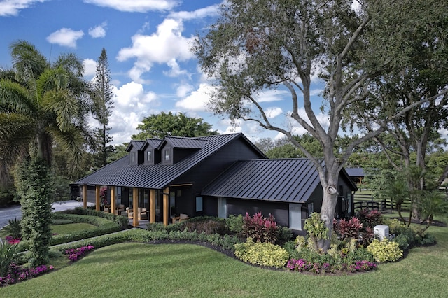 view of front facade with metal roof, a front lawn, a standing seam roof, and fence