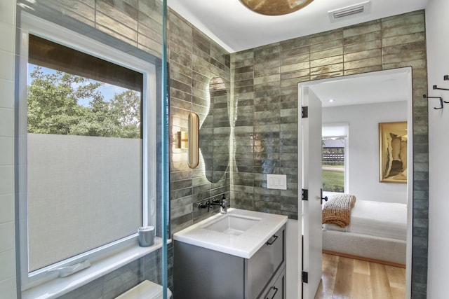 bathroom featuring visible vents, tile walls, ensuite bath, and wood finished floors