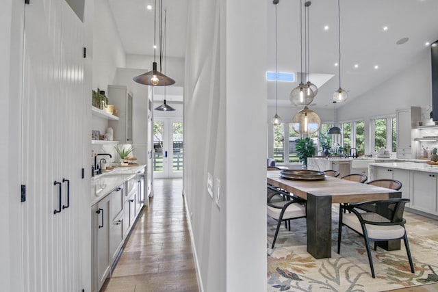 kitchen with a towering ceiling, a healthy amount of sunlight, open shelves, and french doors