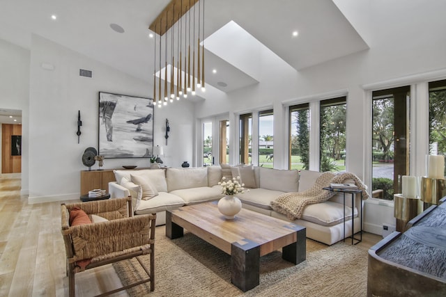 living area featuring high vaulted ceiling, light wood finished floors, plenty of natural light, and visible vents