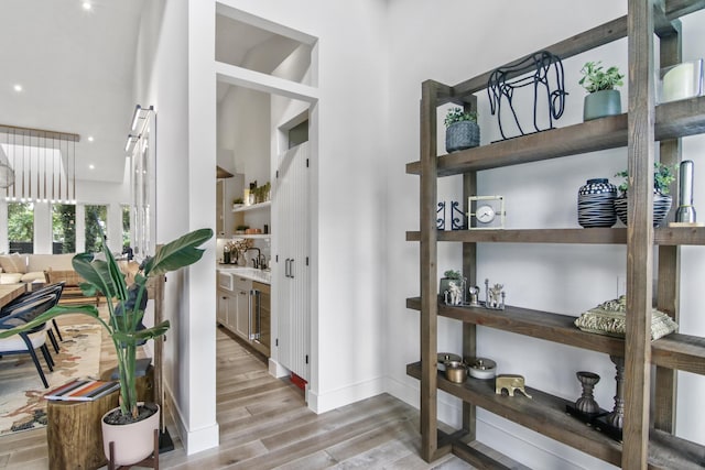 interior space featuring a high ceiling, light wood-style flooring, and baseboards