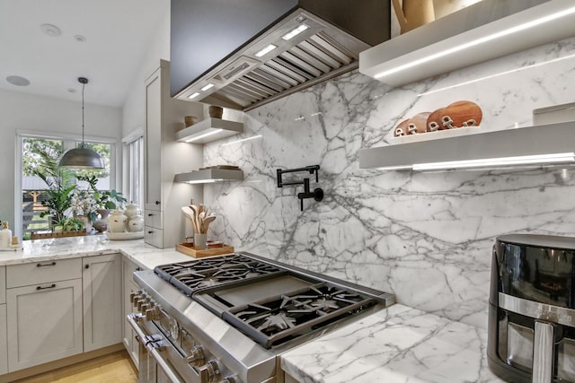 kitchen featuring light stone counters, high end stainless steel range oven, premium range hood, open shelves, and backsplash