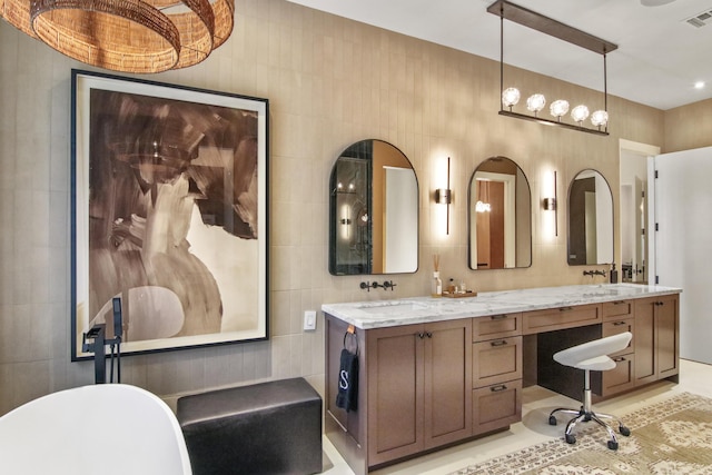 full bathroom featuring a sink, a soaking tub, double vanity, and tile walls