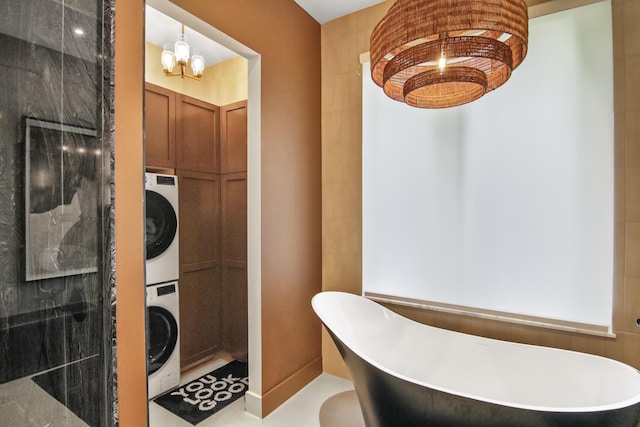 full bath with stacked washer and clothes dryer, a notable chandelier, a freestanding bath, and walk in shower