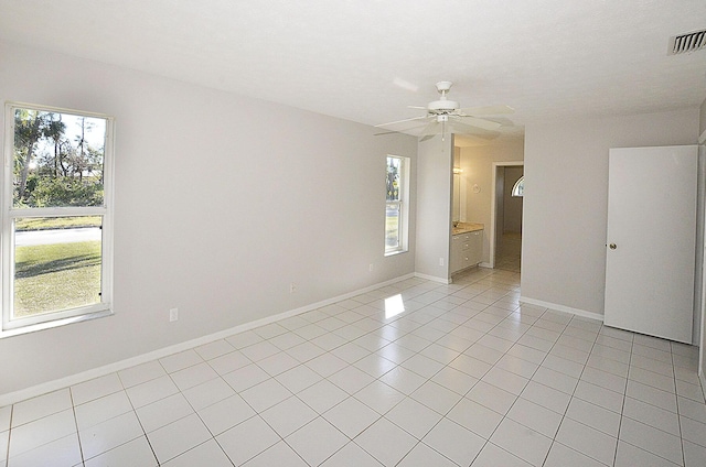 tiled spare room featuring a wealth of natural light and ceiling fan