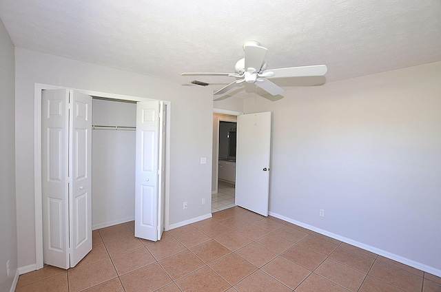 unfurnished bedroom featuring ceiling fan, a textured ceiling, a closet, and light tile patterned floors