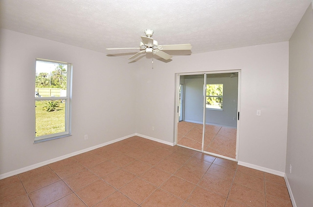 unfurnished bedroom with ceiling fan, tile patterned floors, a textured ceiling, and a closet