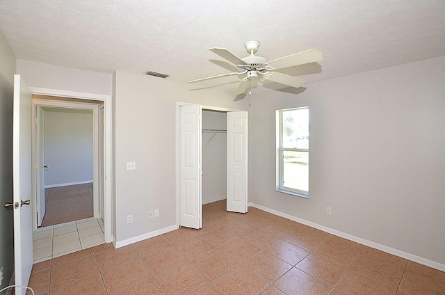 unfurnished bedroom with ceiling fan, a closet, a textured ceiling, and light tile patterned floors