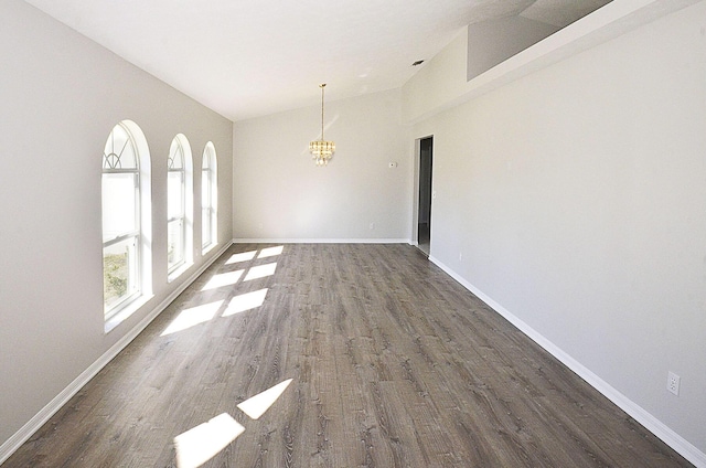 unfurnished dining area featuring vaulted ceiling, dark hardwood / wood-style floors, and a chandelier