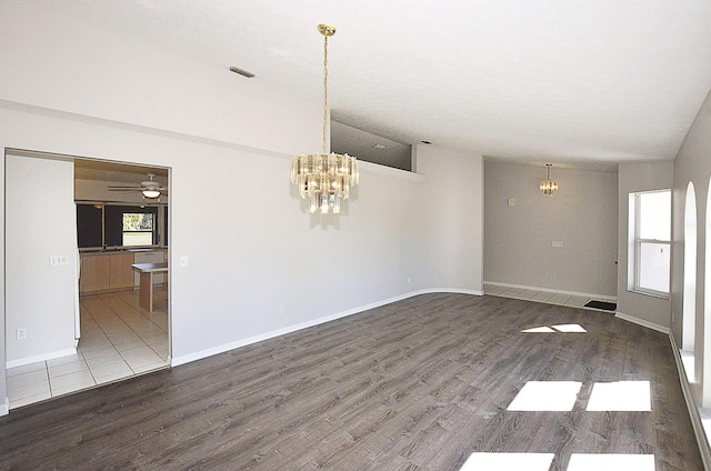 unfurnished room featuring hardwood / wood-style flooring, lofted ceiling, and ceiling fan with notable chandelier