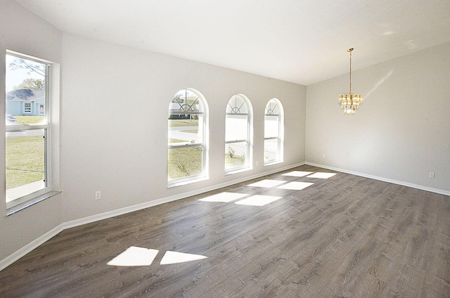 empty room featuring an inviting chandelier, dark wood-type flooring, and lofted ceiling