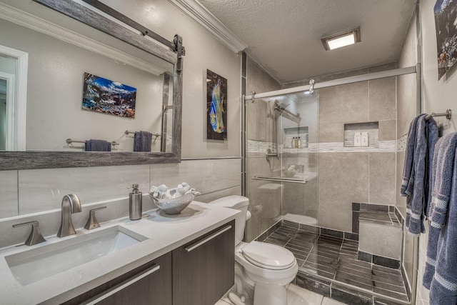 bathroom with tile walls, vanity, an enclosed shower, a textured ceiling, and crown molding