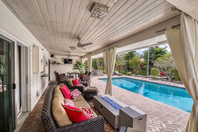 view of pool with an outdoor living space with a fire pit, ceiling fan, and a patio area