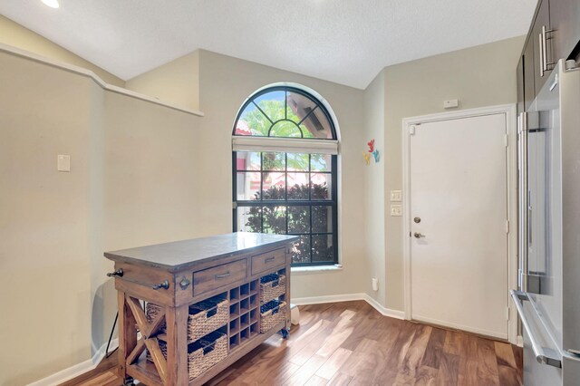 foyer with vaulted ceiling, a textured ceiling, and dark hardwood / wood-style flooring