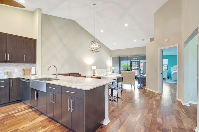 kitchen featuring kitchen peninsula, sink, dark brown cabinets, and light wood-type flooring