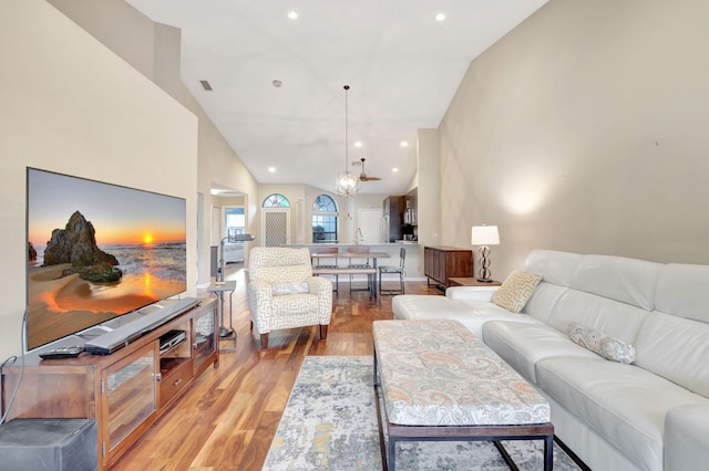 living room featuring high vaulted ceiling, an inviting chandelier, and light wood-type flooring