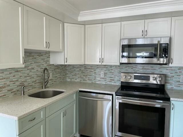 kitchen featuring stainless steel appliances, a sink, white cabinetry, and crown molding