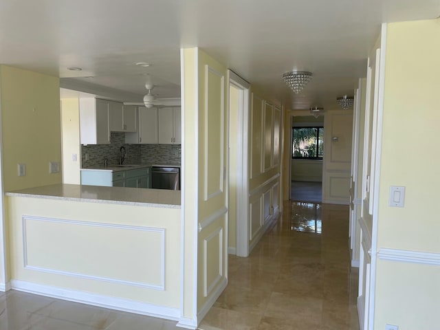 kitchen featuring ceiling fan, a sink, light countertops, decorative backsplash, and dishwasher