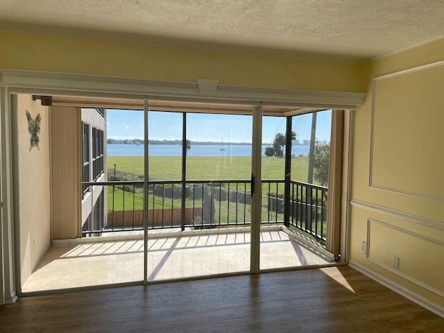 doorway with a textured ceiling, a water view, and wood finished floors