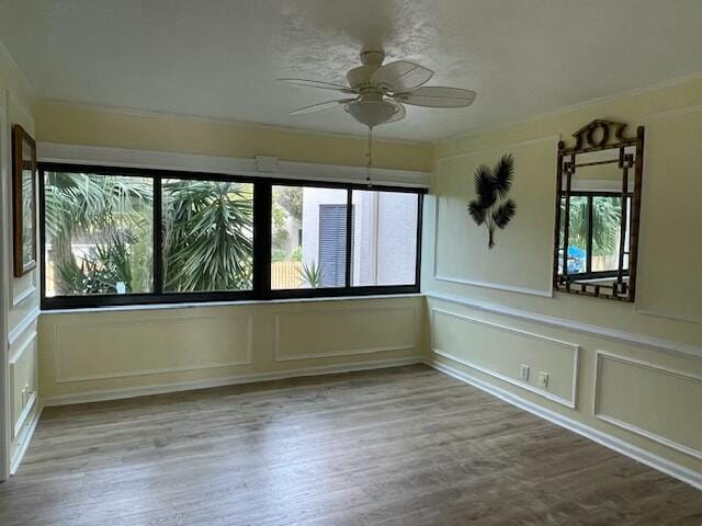 empty room with a decorative wall, a wealth of natural light, and wood finished floors