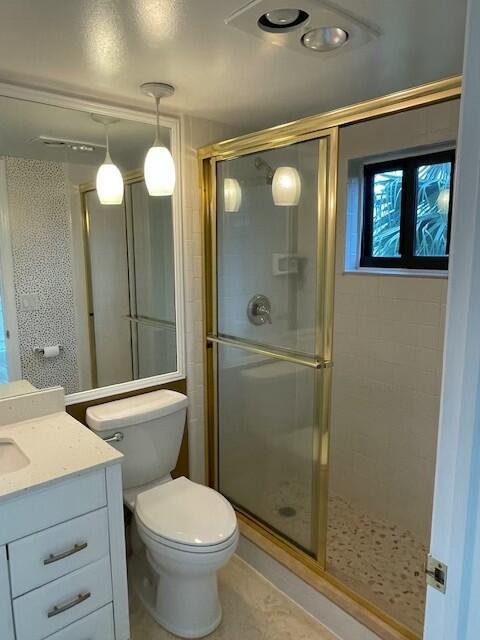 full bath featuring a stall shower, tile patterned flooring, vanity, and toilet