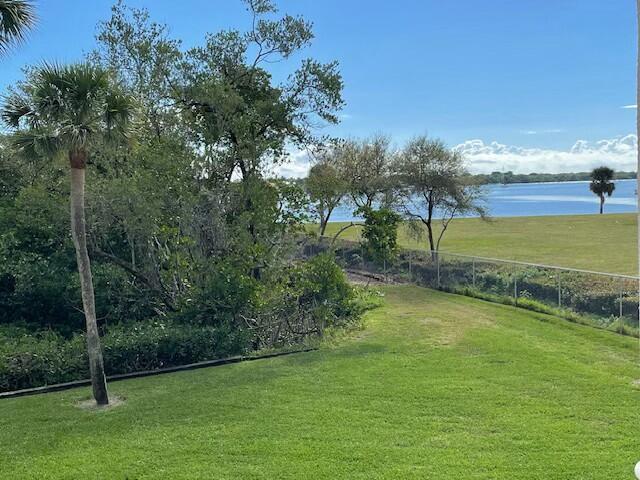 view of home's community with a yard, a water view, and fence