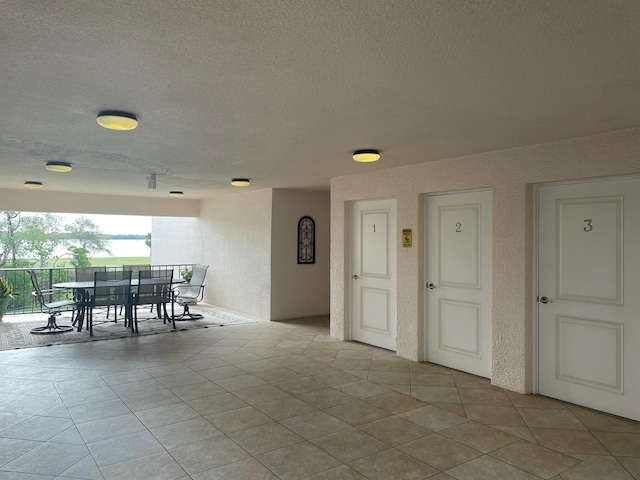 dining space featuring light tile patterned floors, a textured ceiling, and a textured wall