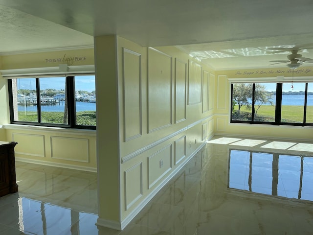 hall with marble finish floor, a healthy amount of sunlight, a water view, and a decorative wall