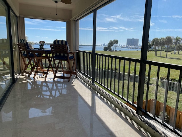 sunroom / solarium featuring a ceiling fan, a water view, and plenty of natural light