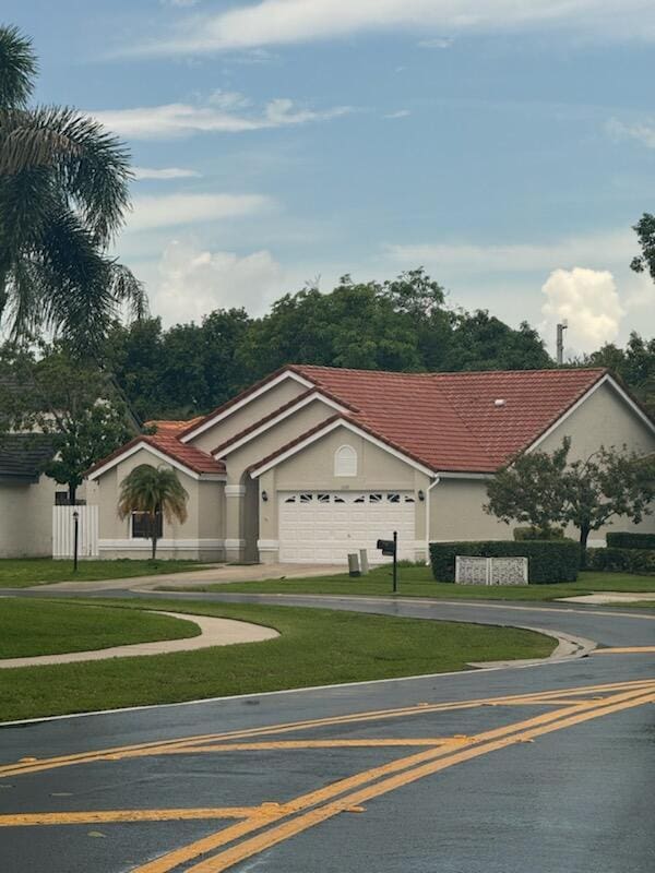 ranch-style house featuring a garage and a front lawn