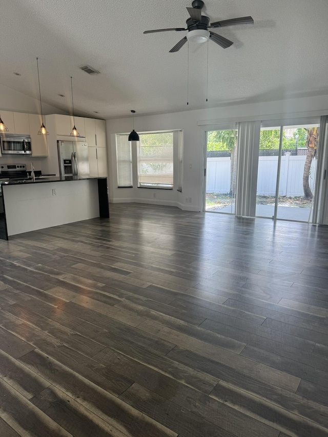 unfurnished living room with ceiling fan, dark hardwood / wood-style flooring, and a textured ceiling