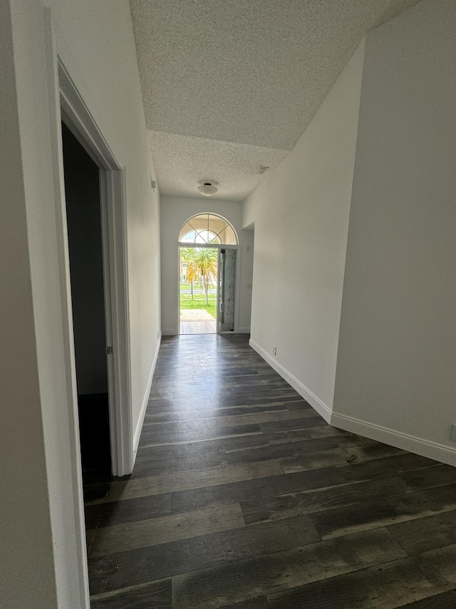 hallway with dark hardwood / wood-style floors and a textured ceiling