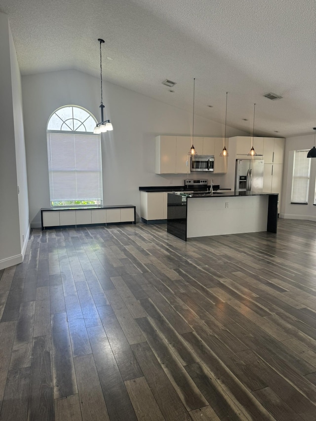 kitchen with baseboard heating, white cabinetry, hanging light fixtures, stainless steel appliances, and a healthy amount of sunlight